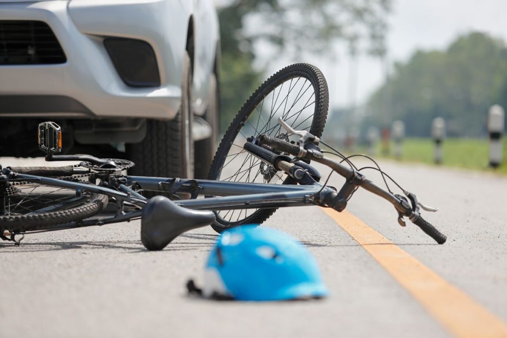 Damaged bicycle and helmet on road after a collision with a white car