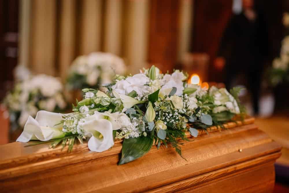 close up picture of a casket with flowers on top at a funeral
