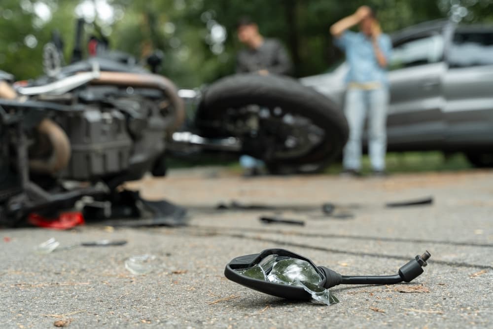 Damaged motorbike and car on the city road at the scene of an accident.