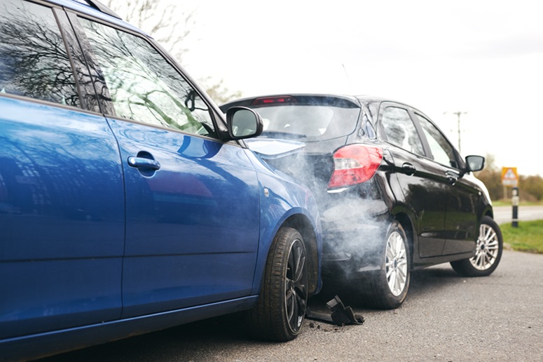 Two cars involved in traffic accident on side of the road with damage to bonnet and fender